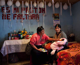 A postnatal visit by a community healthcare worker, in Nahuala, Guatemala.: While checking on the health of the newborn, she also discusses family planning with her client.
